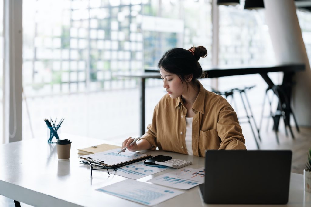 Accountant business woman using calculator and computer laptop, budget and loan paper in office