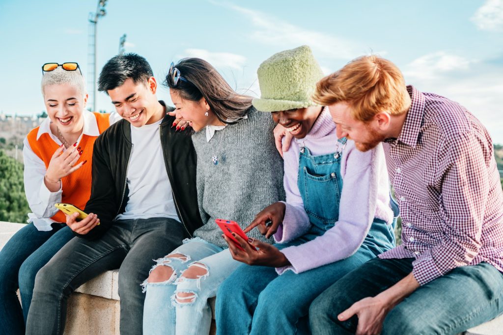 Five multiracial friends watching videos in social media sitting together and having fun.