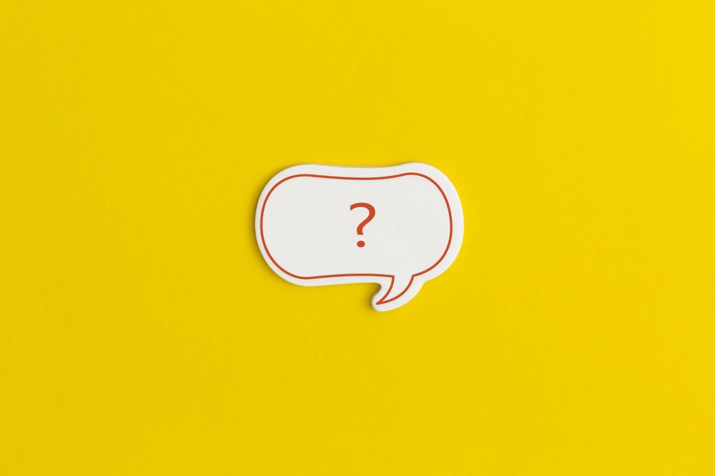 Paper speech bubble on a yellow background. Question mark.