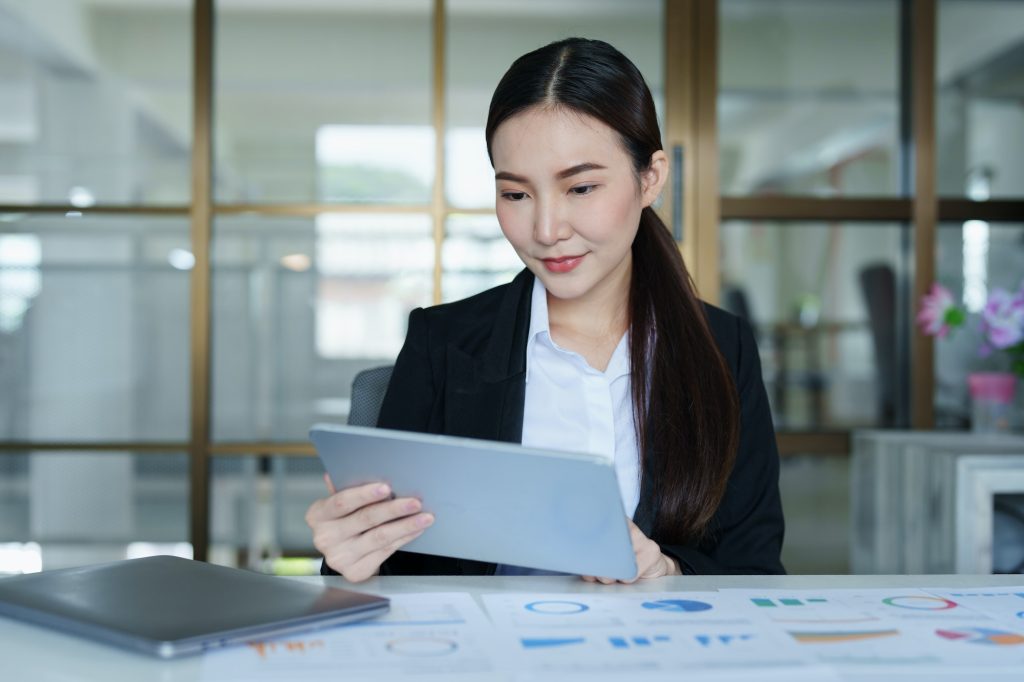 Portrait of a thoughtful Asian businesswoman looking at financial statements and making marketing