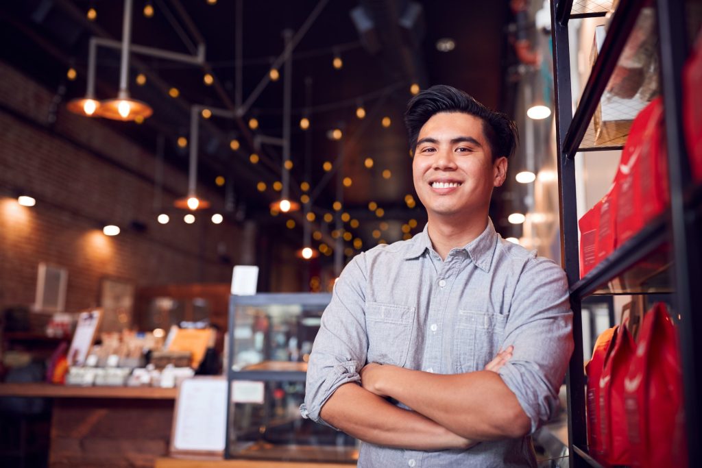 Portrait Of Male Coffee Shop Owner Standing By Counter